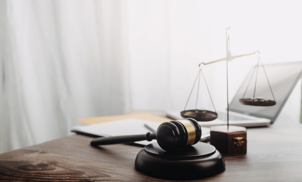 Gavel, scales, papers, and a laptop on a desk