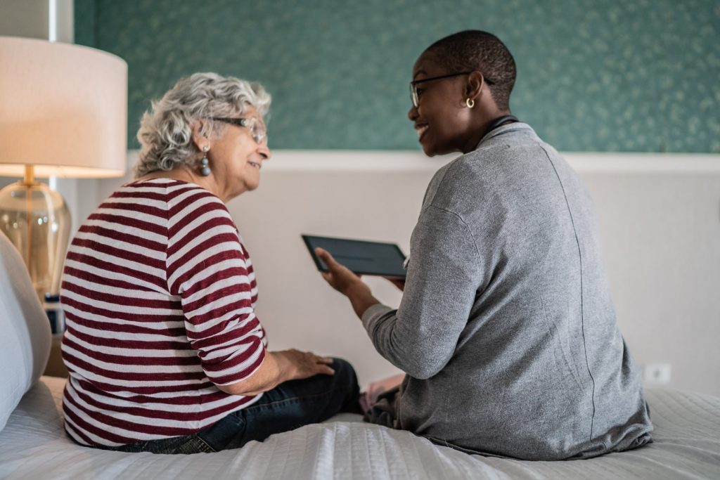 Person with tablet talking to elderly woman