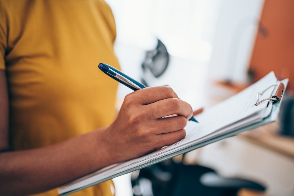 Woman hand writing on a clipboard