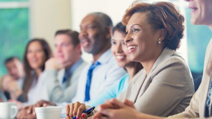 African American businesswoman listening to seminar speaker with others