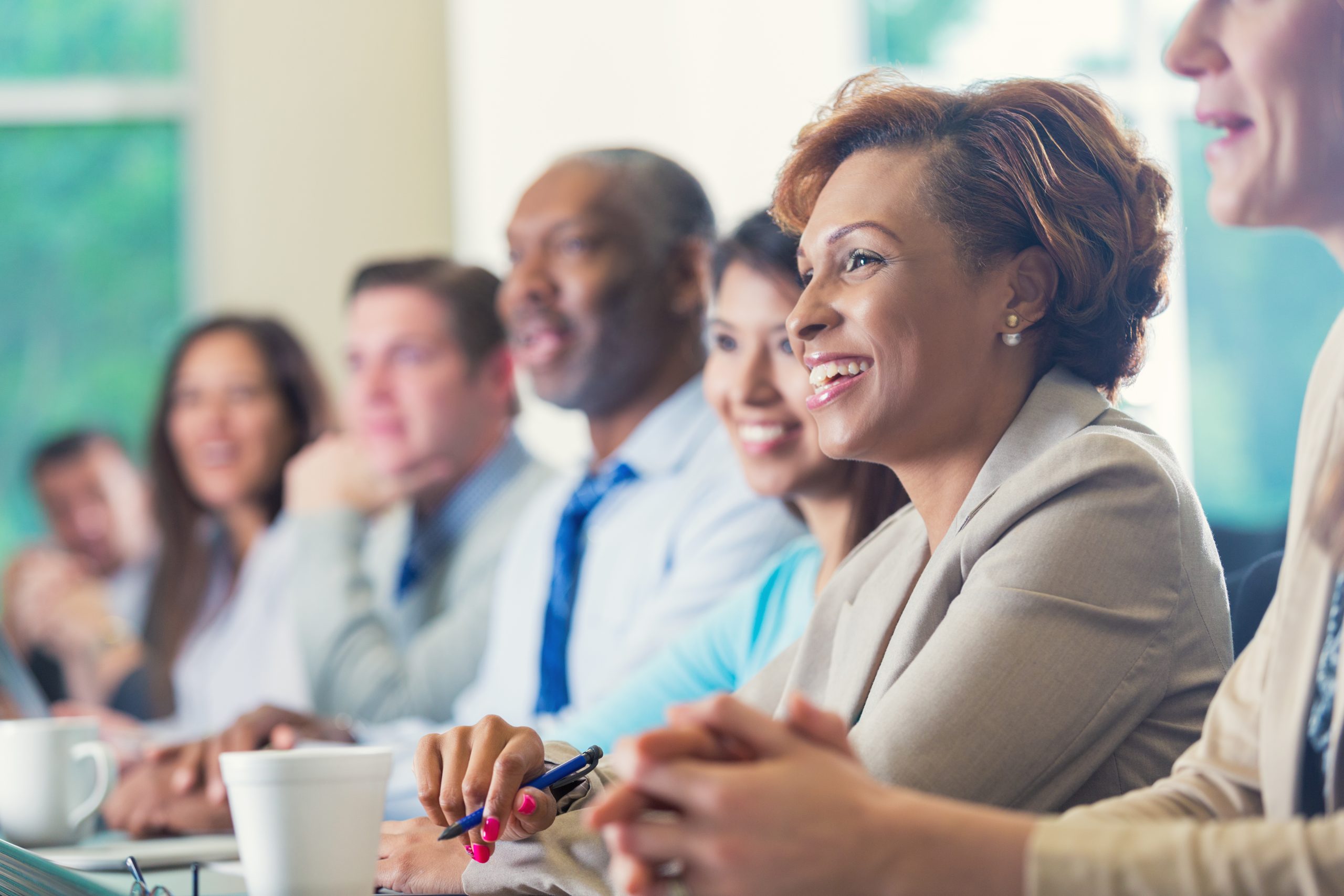 African American businesswoman listening to seminar speaker with others